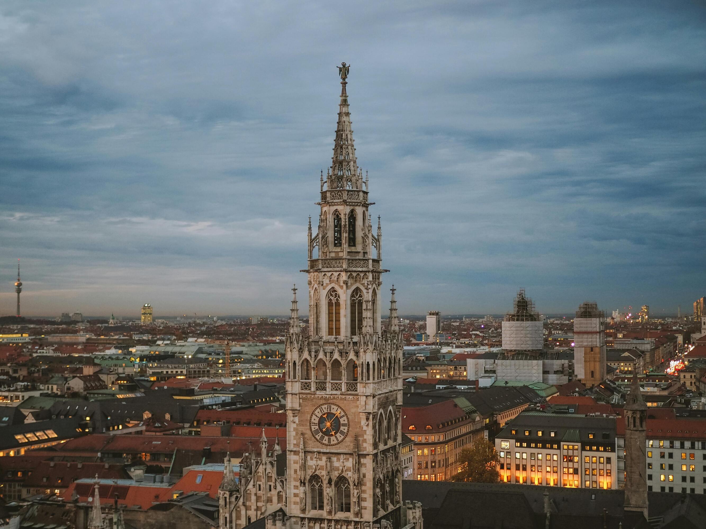 Eine Drohnenaufnahme des Münchner Rathaus mit der Stadt und dem Olympiaturm im Hintergrund.